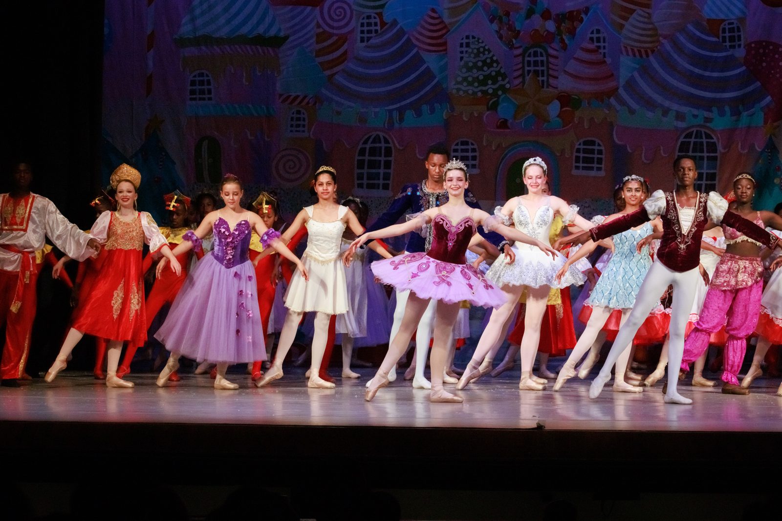 The full cast in colourful costumes in front of the candy castle in the Kingdom of Sweets